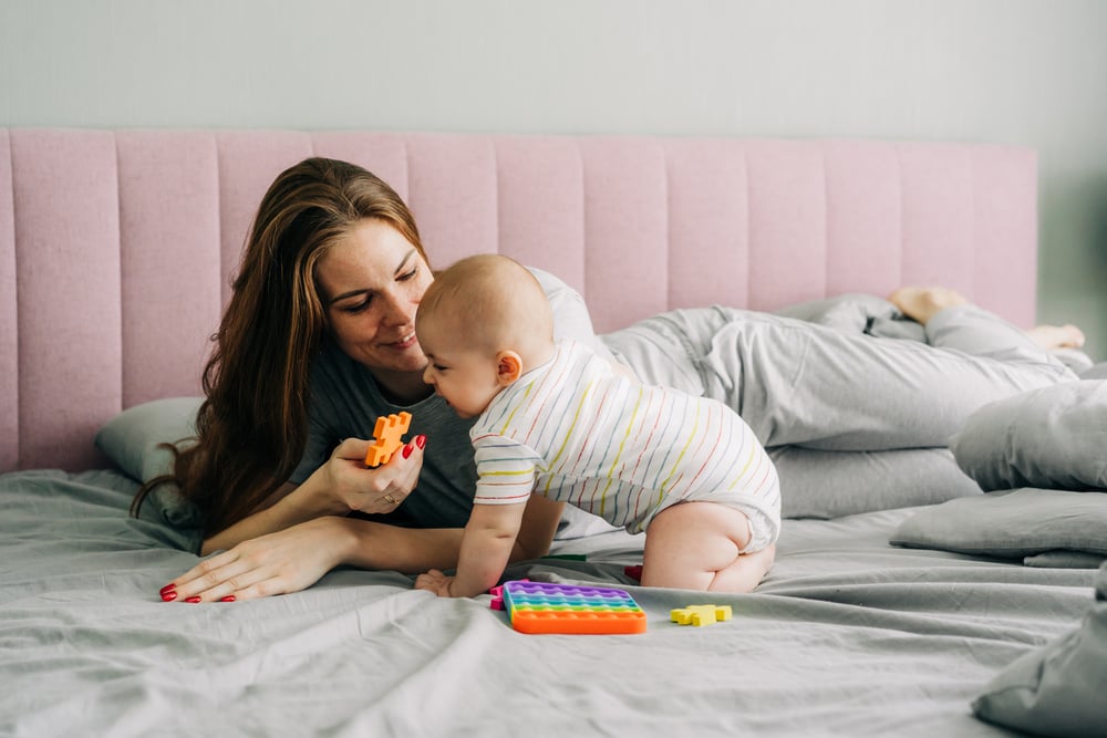 Mother on the Bed with Her Baby Playing Toys.